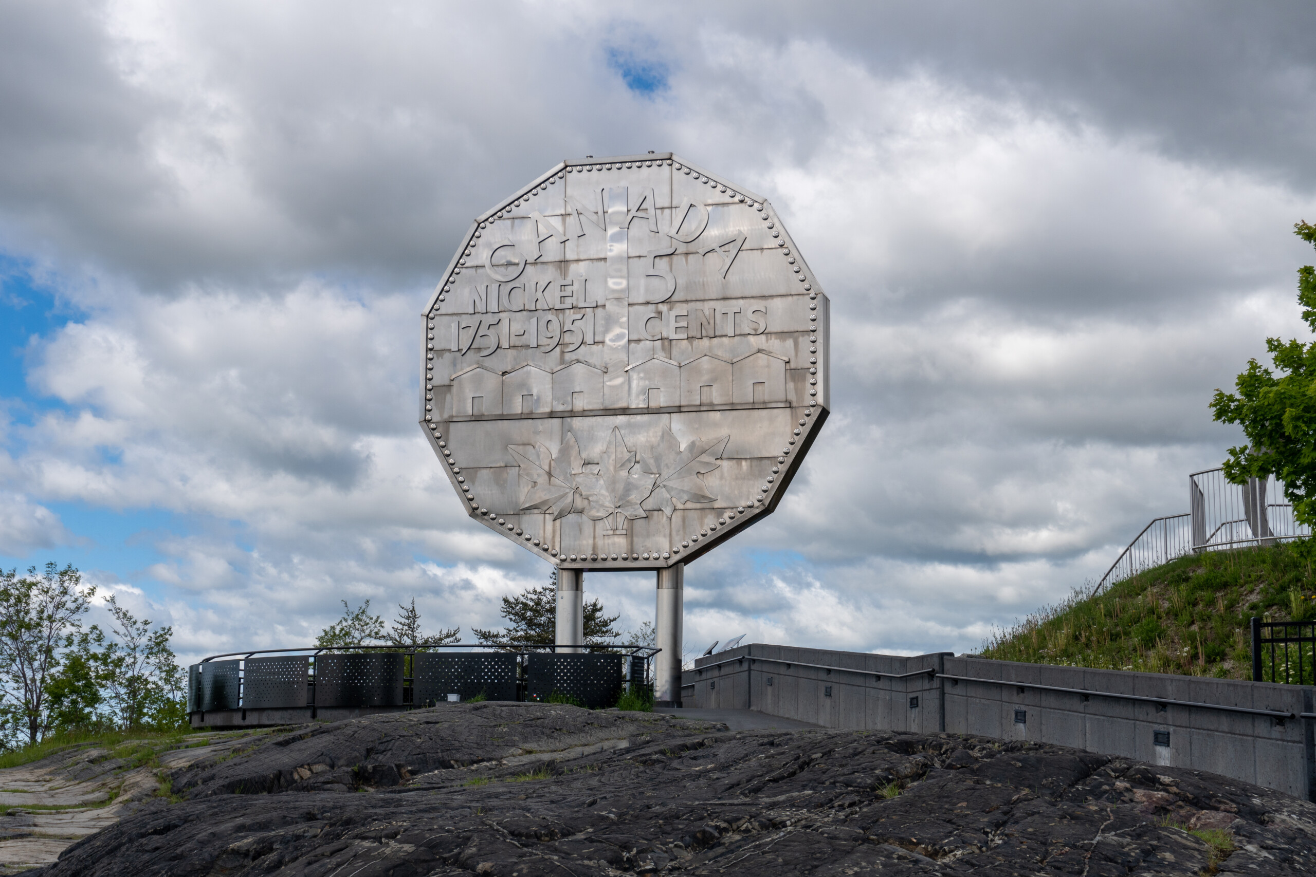 Big Nickel in Sudbury, Ontario, Canada. Giant replica of a 1951 Canadian nickel at Dynamic Earth science museum. Canadian nickel refinery chimney. Enhance Your Community Program